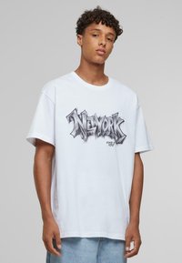 Hvid bomulds t-shirt med en sort, stiliseret "NEW YORK" grafik i centrum. Løs pasform med korte ærmer og rund halsudskæring.