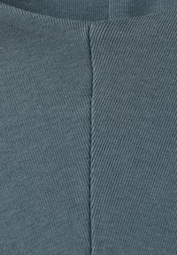 Close-up van blauwgrijze stof met een opvallende verticale naad en fijne diagonale geribde breistructuur.