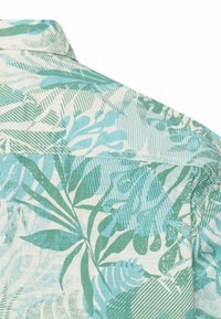 Kraag en bovenrug van een shirt met groene en blauwe tropische bladpatronen op een witte achtergrond.