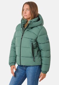 Zielona kurtka puchowa z kapturem, z pikowanym wzorem, zamkiem z przodu, dwiema bocznymi kieszeniami i elastycznymi mankietami. Szczegóły tekstowe na rękawie.