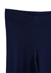 Námořnická ribová látka s elastickým pasem a bezešvým designem. Hladká textura s mírným elastickým efektem, upravená na přiléhavý vzhled.