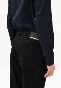 Zwarte spijkerbroek van denim met een gestructureerd oppervlak en rechte snit, gecombineerd met een marineblauwe lange mouwen shirt. Bevat het ARMADENGELS-logo op de tailleband.