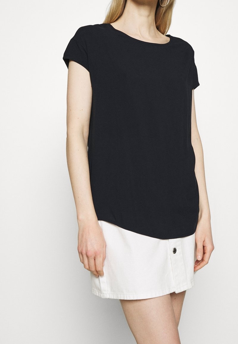 Black short-sleeve t-shirt with a round neckline, soft fabric, and a slightly curved hem, paired with a white denim mini skirt.