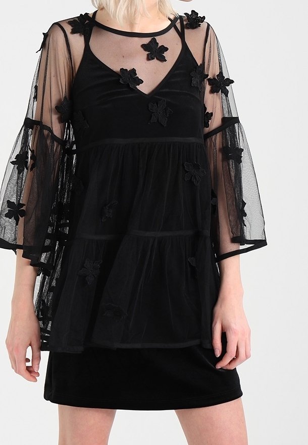 Czarny top z haftem kwiatowym, z przezroczystymi, siateczkowymi rękawami i warstwowym fasonem. Posiada dekolt w kształcie litery V oraz teksturowane akcenty kwiatowe w całej konstrukcji.