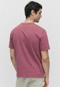 Kortærmet t-shirt i falmet mauve bomuld, rund halsudskæring, afslappet pasform, glat tekstur, minimale sømdetaljer.