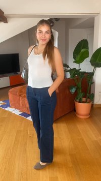 Λευκό ριβέ αμάνικο μπλουζάκι, ναυτικά μπλε παντελόνια με τσέπες, γκρι μπαλαρίνες. Λείος υφασμάτινος τύπος, casual σχέδιο σε φωτεινό εσωτερικό περιβάλλον με φυτά.