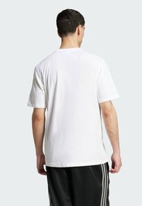 Hvid bomulds t-shirt med afslappet pasform, korte ærmer og rund hals. Synlige sømme og en flad kant i bunden.