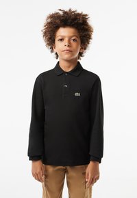 Black long-sleeve polo shirt with a collar, featuring a green crocodile logo. The fabric appears smooth with a subtle texture.