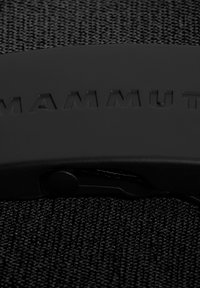 Svart nylonrem med matt svart plastspänne. "MAMMUT" präglat på spännet. Texturerad tyg synlig under.