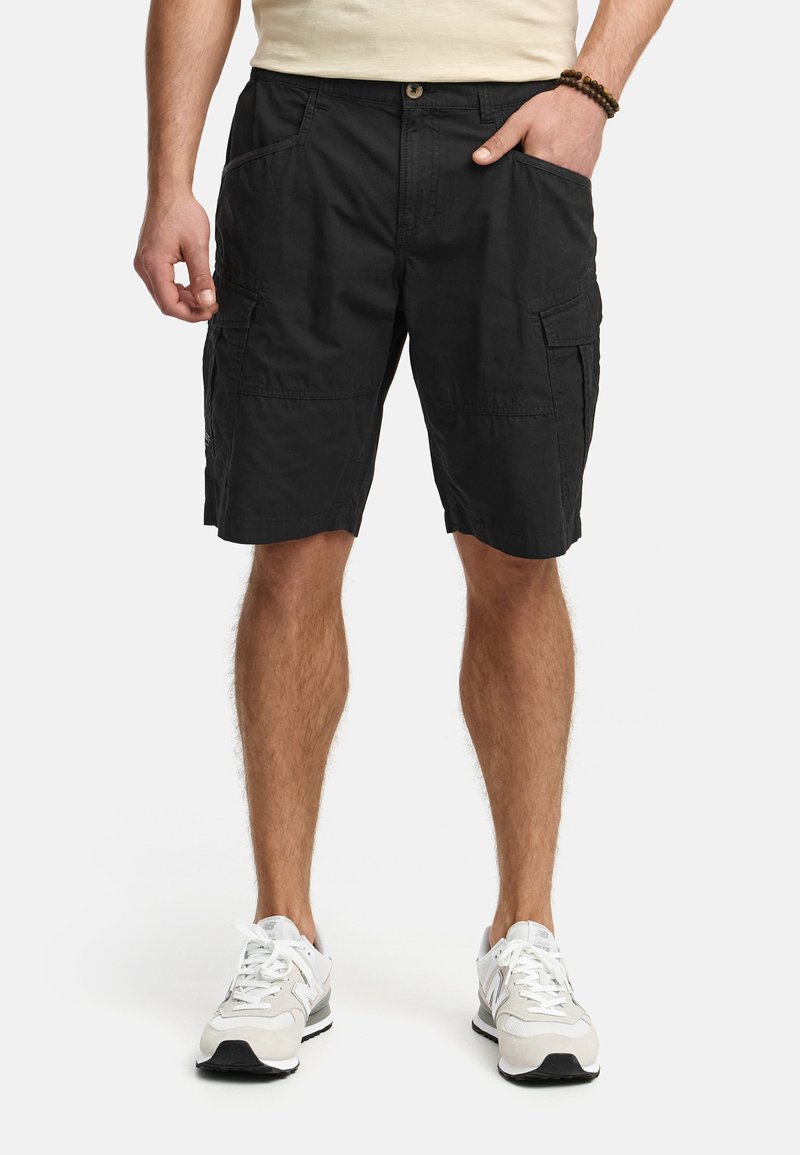 Shorts cargo noirs en coton avec plusieurs poches, une taille ajustée et un design droit. Associés à des baskets grises et blanches.
