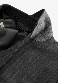 Schwarze Jacke mit einem dezenten Nadelstreifenmuster, ausgestattet mit einem weichen grauen Filzkragen und einem satinierten Innenfutter mit floralen Akzenten.