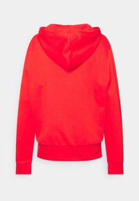 Sweat à capuche rouge avec une texture douce. Comprend une poche kangourou ainsi que des poignets et un ourlet côtelés. Design simple avec un dos uni.