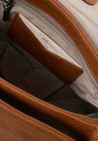 Brauner Leder Geldbeutel mit strukturierter Oberfläche, ausgestattet mit einem sichtbaren Kartenfach und einem hellgrauen Innenfutter. Reißverschluss-Detail vorhanden.