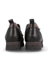 Zapatos de cuero negro con parte superior de tela texturizada en gris, tacón bajo y tiradores en la parte posterior. El diseño presenta una silueta elegante y redondeada.