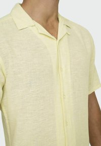 Lichtgele short-sleeve shirt gemaakt van een gestructureerde, lichtgewicht stof met een knoopsluiting aan de voorkant en een klassieke kraag.