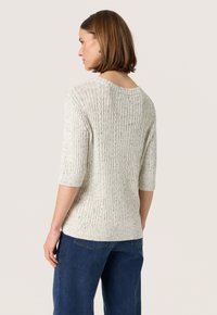 Ljust grått ribbat stickat tröja med 3/4 ärmar, med en vid halsringning och strukturerat mönster. Bärs med blå denimbyxor.