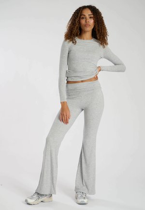 Top gris de manga larga con detalle retorcido y pantalones acampanados a juego; tejido suave y elástico con una textura lisa. Calzado deportivo casual.