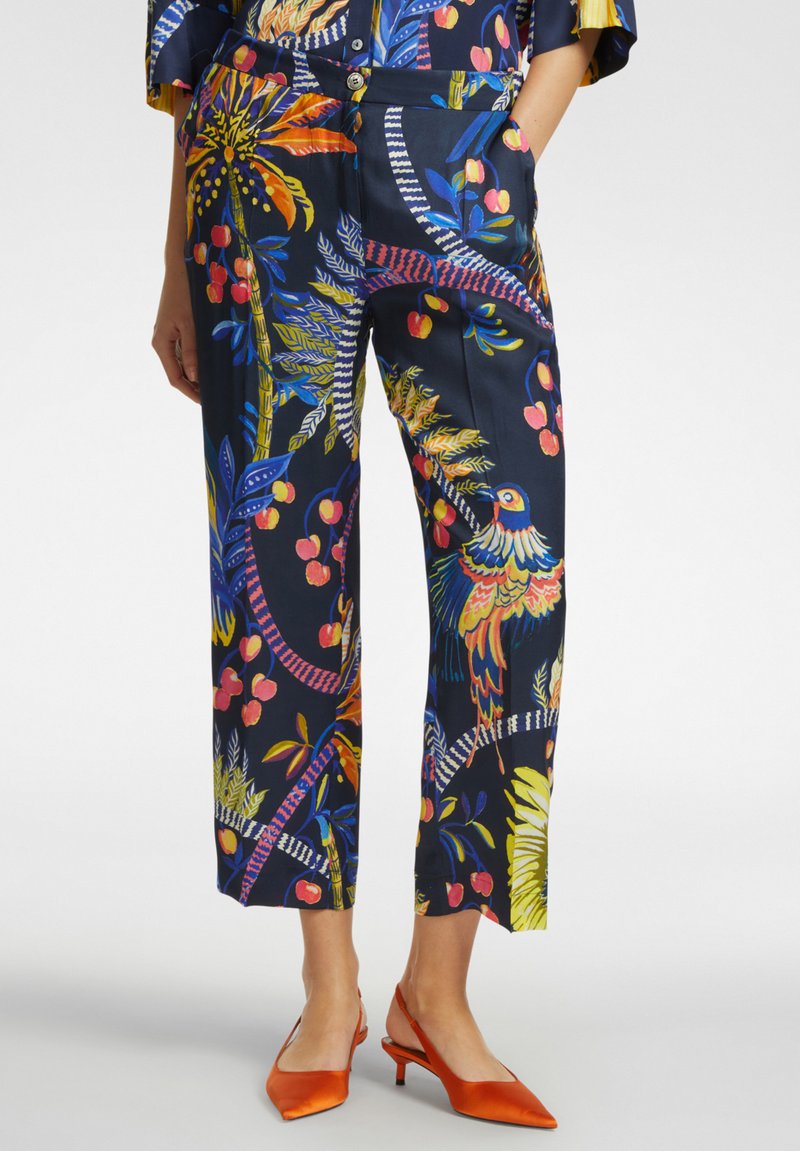 Pantaloni con un vivace motivo floreale e di uccelli in giallo, rosa e blu su uno sfondo scuro, dalla vestibilità rilassata e dotati di tasche.
