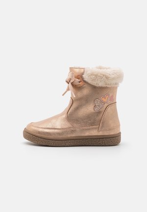 Botte d’hiver métallique rose pour enfant avec bordure duveteuse, lacets latéraux et décorations en forme de cœur sur le côté.