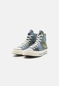 Scarpe sportive alte con un motivo di colore in gradiente che va dal blu al verde, materiale in tela, lacci bianchi e suola in gomma con strisce laterali.