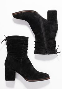 Bottines en daim noir à design décontracté, bout arrondi et talon épais texturé. Dotées d'une fermeture éclair intérieure et d'un cordon de serrage ajustable.