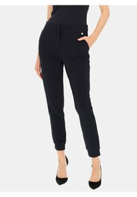Granatowe spodnie o dopasowanym kroju, z tapered nogawkami, gładką teksturą, bocznymi kieszeniami oraz metalowym akcentem przy pasie. Charakteryzują się klasycznym krojem.