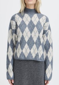 Maglione grigio a motivo a rombi con collo alto, caratterizzato da rombi blu chiaro e blu scuro. Realizzato in morbido materiale lavorato a maglia, con maniche lunghe.