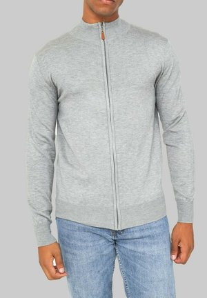 Gilet zippé gris clair avec un col haut, des poignets et un ourlet côtelés, fabriqué en matériau tricoté doux, présentant un accent en cuir avec un bouton en cuir.