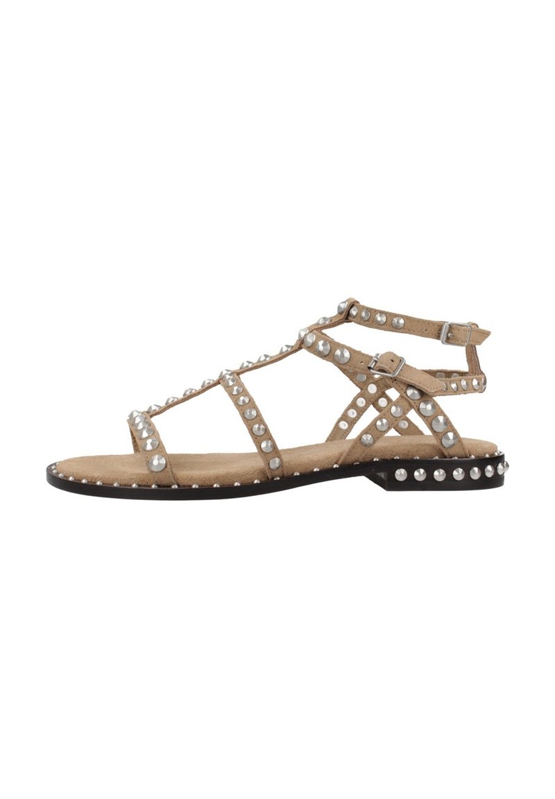 Sandal in finta suede beige con borchie argentate, caratterizzato da un design a strisce, suola piatta e chiusura con fibbia alla caviglia. Accenti decorativi lungo i bordi.
