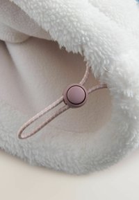 White faux fur fabric with a smooth inner lining, featuring a thin pink drawstring and round toggle for adjustment.