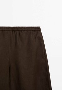 Bruine linnen broek met een elastische tailleband en zijzakken; gladde textuur, eenvoudig ontwerp en geen zichtbare patronen of hardware.