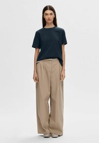 Dark blue cotton t-shirt paired with loose beige trousers. The outfit features a minimalist design with short sleeves and a simple cut.