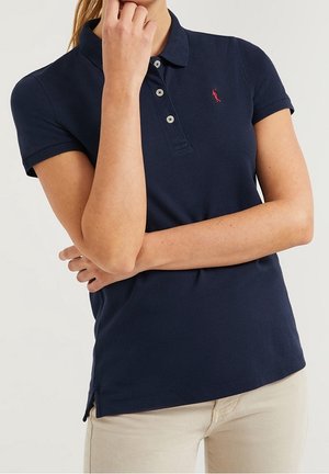 Marineblå polo skjorte lavet af bomuld med en to-knaps stolpelukning, broderet logo på brystet og korte ærmer. Sideslids ved kanten.