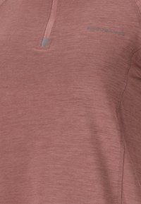 Close-up van een dusty rose lange mouwen sporttop met een kwart ritssluiting en het "ENDURANCE" logo op de linkerborst.