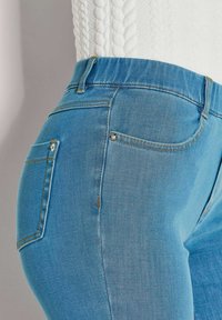 Lichtblauwe spijkerbroek met een getailleerd ontwerp, voorzien van een klassieke vijfzakstijl, zichtbare stiksels en een middelhoge tailleband.