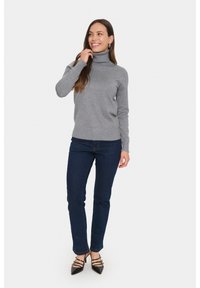 Pulover gri cu guler înalt asociat cu blugi negri. Puloverul are un design ajustat, textură canelată și mâneci lungi. Pantofii negri cu toc completează ținuta.