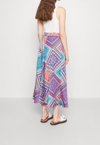 Barevná, elegantní maxi sukně s geometrickými vzory v purpurové, tyrkysové, oranžové a růžové barvě. Vyrobena z lehkého materiálu, má přiléhavý pas.