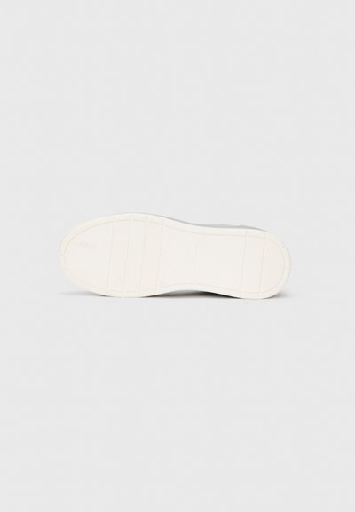 Semelle de sneaker blanche en caoutchouc texturé, comportant des rainures horizontales et une zone de talon lisse. Pas de marquage ou de motifs visibles.