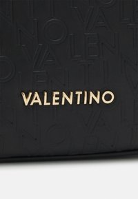 Černá strukturovaná kabelka s vyvýšeným logem a zlatým emblémem "VALENTINO". Hladká kožená materiál s minimalistickým designem.