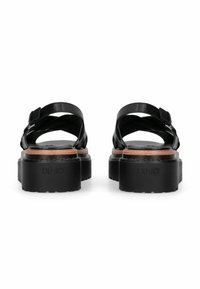 Zwarte leren platformsandalen met een dikke zool, gekruiste bandjes en een verstelbare gesp. Voorzien van een reliëflogo aan de zijkant.