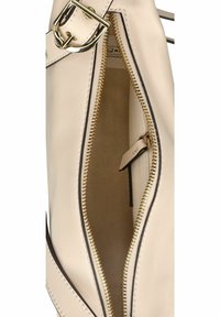 Borsa in pelle crema con zip dorata, che mostra la fodera interna. Presenta un piccolo tag attaccato all'interno e dettagli cuciti.