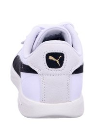 White and black athletic shoe with a textured leather heel, gold logo on the back, and padded tongue, featuring a smooth rubber sole.
