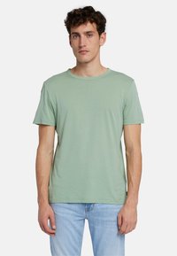 T-shirt a maniche corte, collo rotondo, in misto cotone di colore verde chiaro. Tessuto liscio, vestibilità comoda e design semplice senza fantasie o accenti.