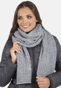 Écharpe en tricot gris avec un motif texturé, présentée enroulée autour du cou, fabriquée dans un matériau doux et chaud avec des bords finis.