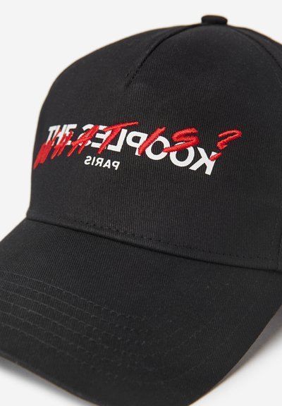 Melns beisbola cepure ar izšūtu tekstu baltā un sarkanā krāsā, ar izliekto vizu un teksturētu audumu. Dizainā ir iekļauti vārdi "Kooples" un "Parīze."