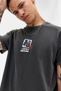 Sötét szürke, túlgombolt póló textúrált anyagból, fehér és piros grafikai nyomattal, amelyen a "LUCKY MISTAKE" felirat középen található a mellkason.