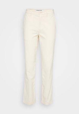Beige Slim-Fit Hose mit Gürtelschlaufen, vorne mit Knopf und Reißverschluss sowie Seitentaschen, vor weißem Hintergrund dargestellt.