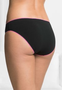 Pantaloni hipster neri in cotone con cintura elastica ondulata rosa e aperture per le gambe. Tessuto liscio, design a copertura minimale.