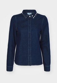 Camicia di jeans blu scuro con maniche lunghe, colletto a bottoni e dettagli in metallo sul colletto. Presenta una chiusura frontale con bottoni e dettagli sulle cuciture.