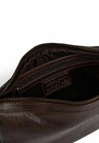 Brun läderväska med en dragkedjeöppning. Inuti finns en mindre ficka med dragkedja och ett tygfoder. Texturerad yta med lätt glans.